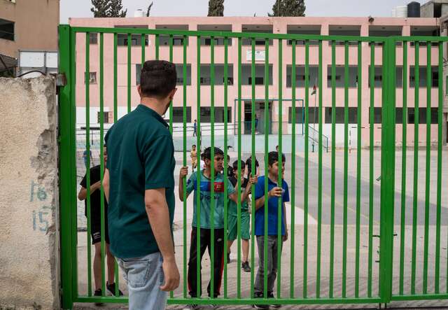 Palestinian teacher Ali* greets his students outside the school. 