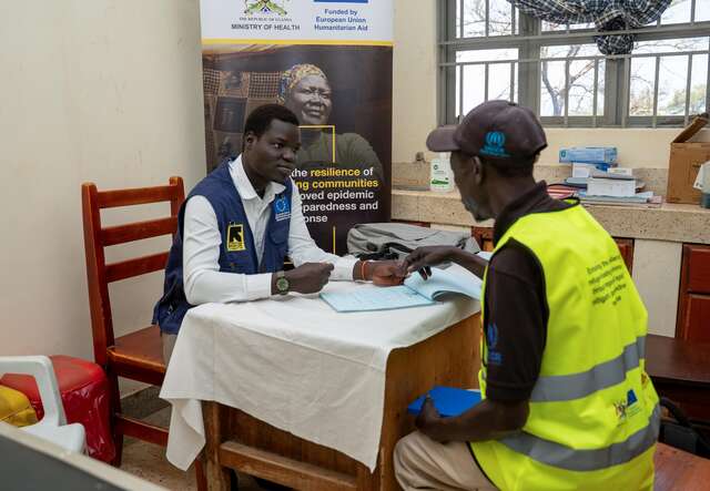 The link between community and clinic: an IRC staff member meets with a village health team supervisor to review records—this coordination has helped turn early warnings into timely treatment across the settlement.