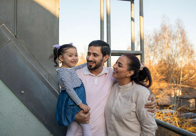 Bahar*, Afrif* and their daughter Mina* enjoy the evening sun at the balcony of their new home in Berlin.