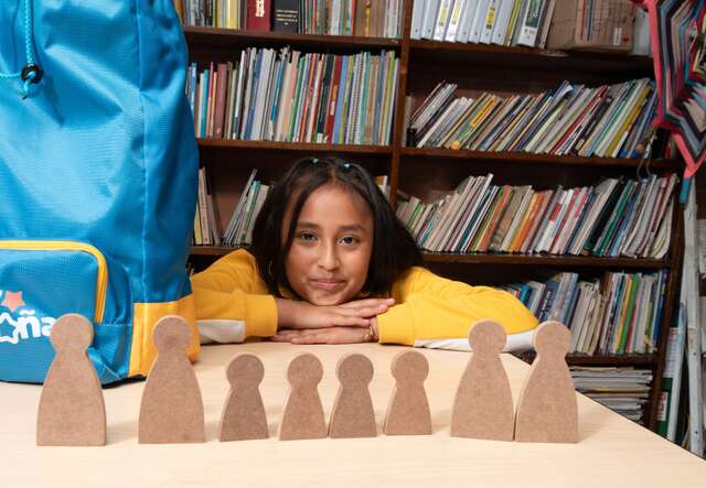 A girl in a yellow shirt poses for a photo at a playful learning session hosted by the IRC.