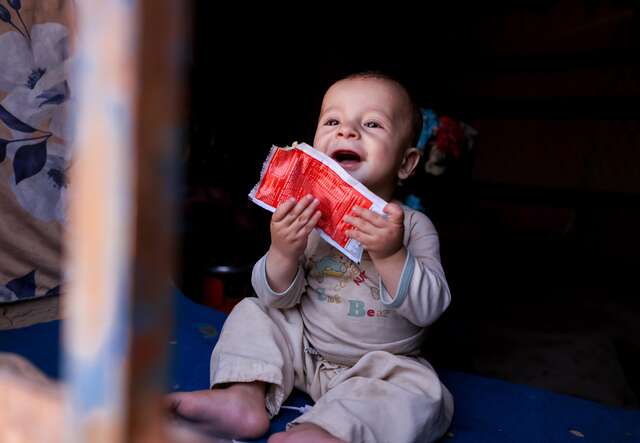 At home, Sahil smiles as he holds one of the sachets of ready-to-use therapeutic food (RUTF) provided by the IRC. “When he's home and healthy, I'm at peace,” Afsana remarked. 