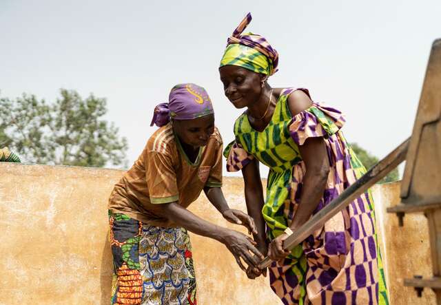 Andrienne helps her sister-in-law Hortense use the well, where access to safe water is helping families stay healthier and easing the burden of daily life.