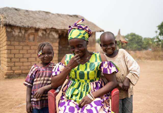 Andrienne sits, laughing with her grandchildren. For her family, the new well has brought safer water and a more secure daily life.