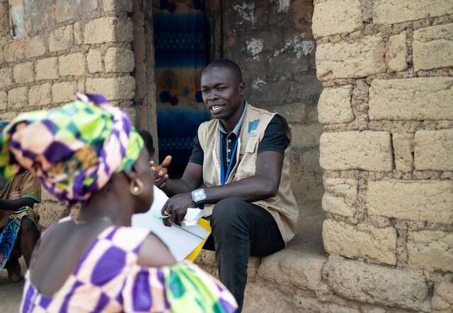 An IRC staff member advising Andrienne on how to encourage her children and family members to regularly wash their hands and use only water from the well.