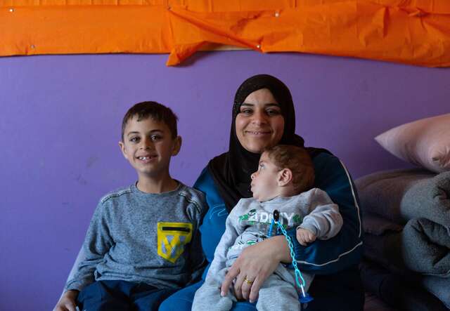 Warda, 28, sits with two of her children, Houssam, 7, left, and Mohammed, 1, on a mattress in the classroom where she lives with her family at a collective shelter where displaced families have found refuge.