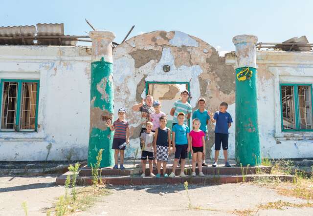 Children stand outside a war-damaged community hall in Ukraine, where the IRC provides medical and legal aid.