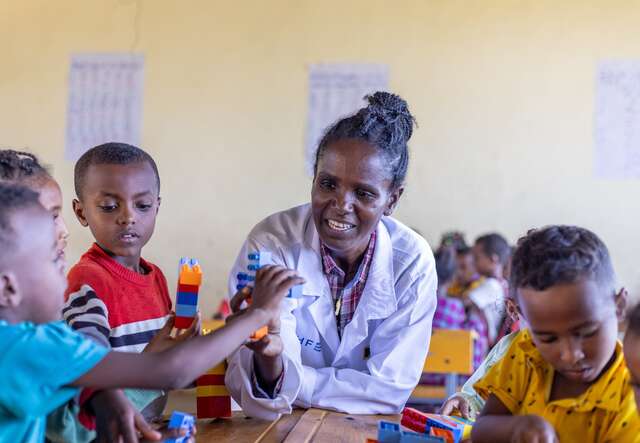 Ms. Baraki sits alongside her students in Ethiopia showing them a lesson using LEGO blocks.