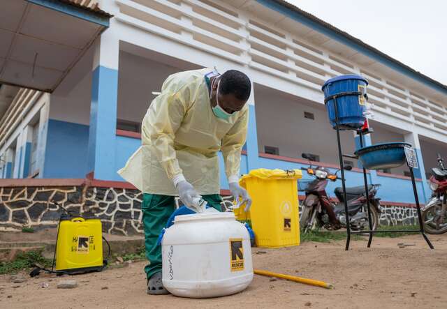A health worker prepares to sanitize a hospital courtyard in DRC, with supplies provided by the IRC.