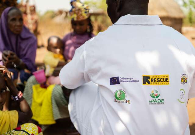 An IRC health worker sits together with residents from the village during their regular check-ins with the community.