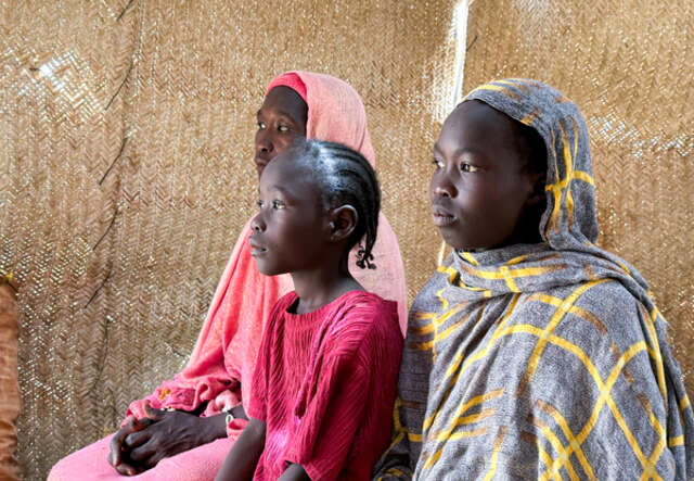 Hawa (45), sits with two of her children, Islam and Asrar at their shelter.