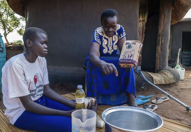 Margret, 16, and her grandmother, Beatrice, sit in the compound of their home in Pagirinya Refugee Settlement, Uganda.