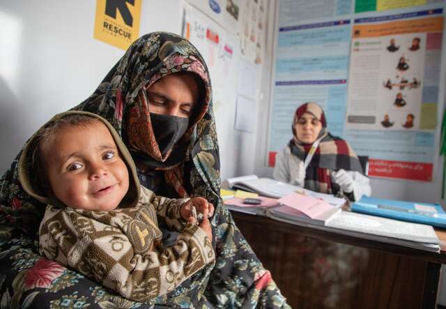 A mother holds her three-year-old child in her arms, as the pair visit an IRC health center in Afghanistan.