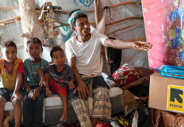 Ahmed inside his makeshift shelter with his children, Mohammed (6), Ali (5), and Abdullah (3).