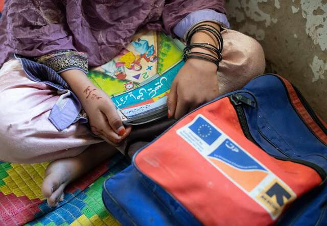 A child seating with books and a back pack with an IRC logo and an EU logo