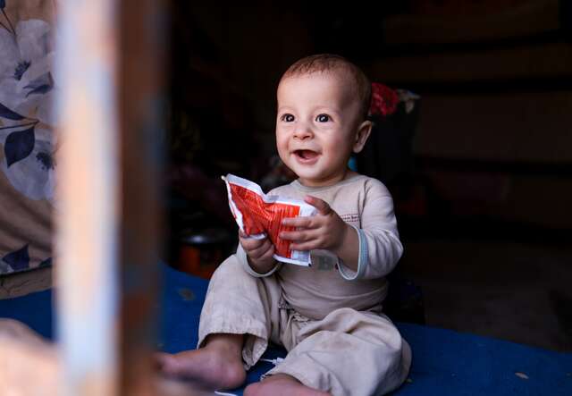 A child holds a packet of malnutrition food treatment.
