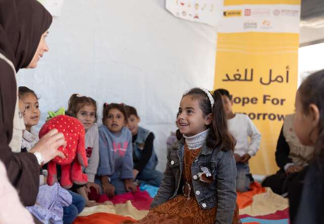 A group of together smile as they attend an IRC-run childhood development session in Gaza.