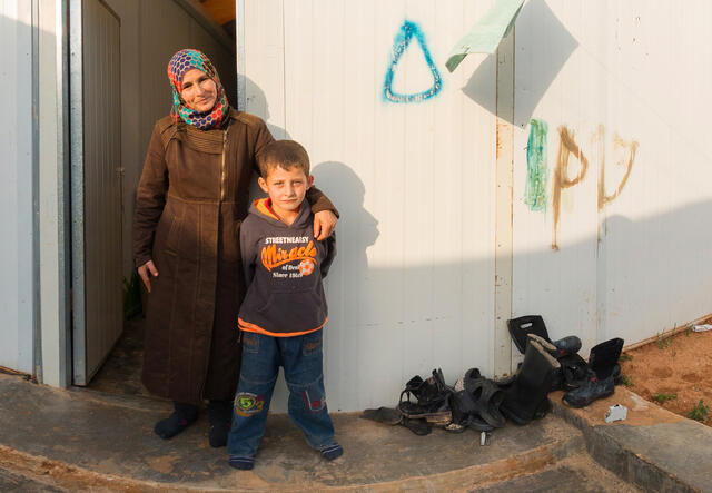 Jamalat Abd al-Raouf al-Hariri stands outside her home in Jordan's Zaatari camp with her seven-year-old son.