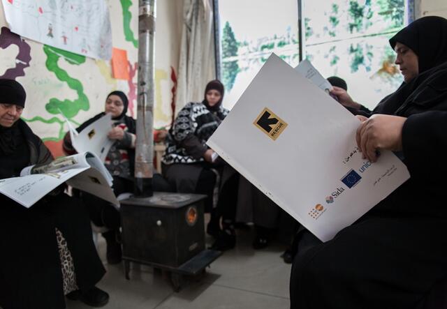 Women focus on the comic book that follows Hala's journey to work as part of an activity at the IRC's women's centre.