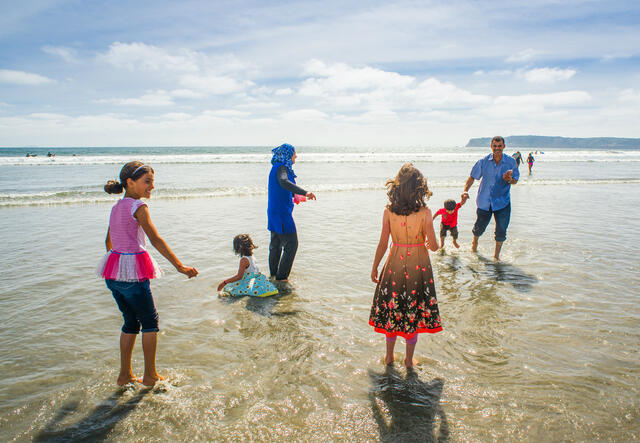 Azzam and Nisreen Tlas and their children play in the surf on a California beach