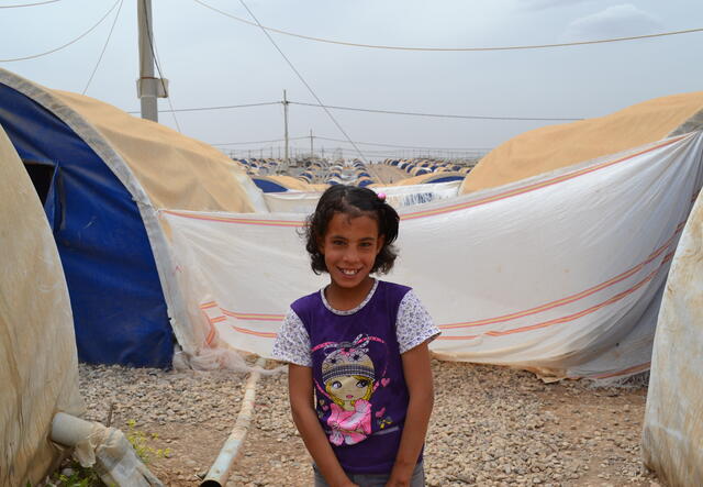 Eleven-year-old Farah outside her family's tent in Nargazilia camp, Iraq