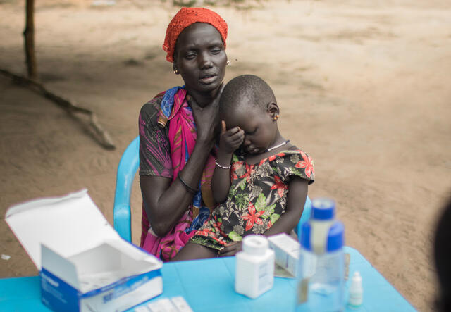 Angelina, with her listless daughter in her lap, describes their symptoms to IRC medical staff at the Kol clinic.