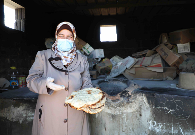 Mariam, a refugee from Syria, holds some bread