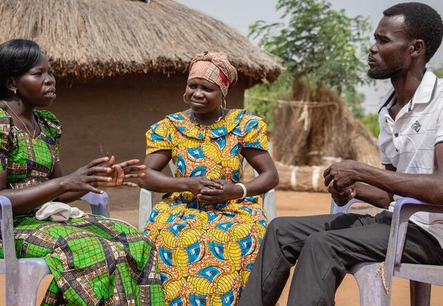 Two women and a man sit in a circle and share a conversation.