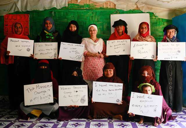 Activist and lawyer Razia Sultana stands with women holding handwritten signs at her women’s center in Ukhiya camp, Cox's Bazar.