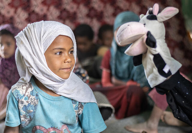 Young girl stares at the cow puppet