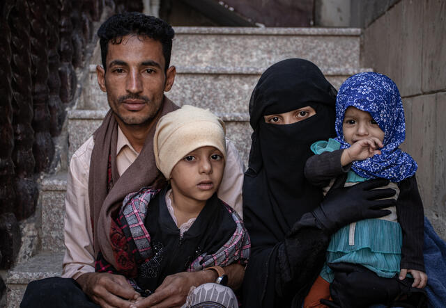 Parents Taqwa and Mohammed sit on steps with their two young children