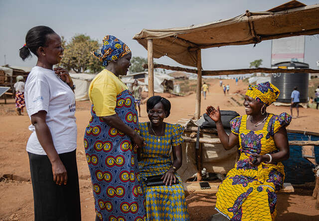 Women from refugee activist Togoleta stand around together laughing.