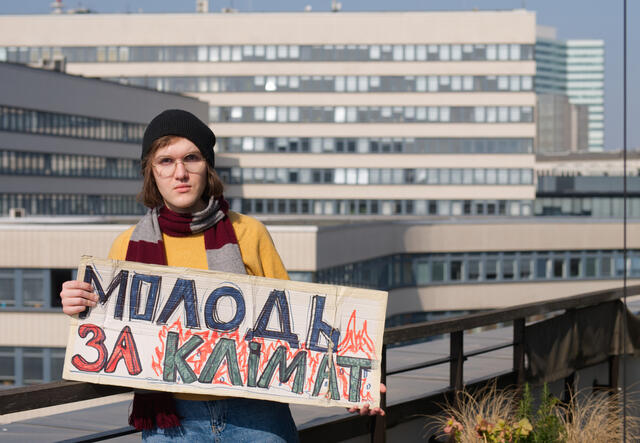 Ilyess holding a sign demanding action against climate change.