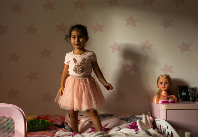 4-year-old Nasrin stands on her bed wearing a pink tutu.