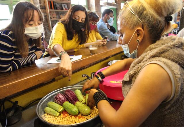 Jacqueline preparing the vegan Mahchi dish with people looking on