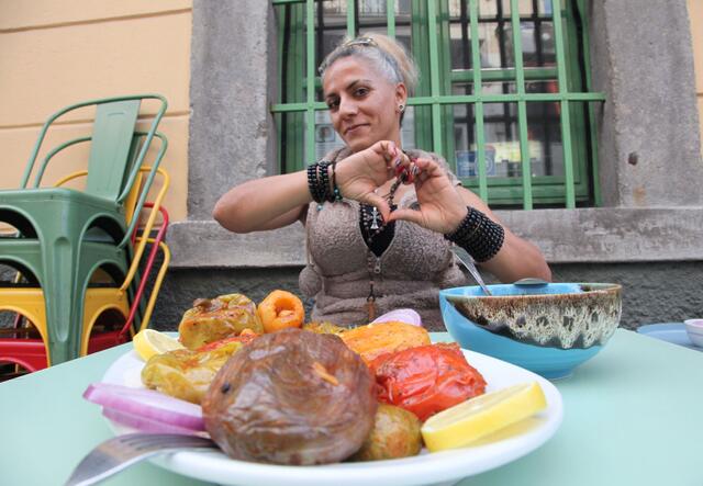 Jacqueline making a heart gesture as she sits at a table in front of a dish of vegan Mahchi