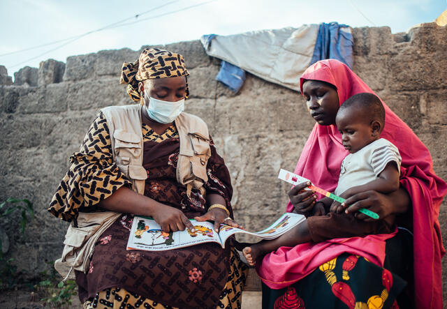 Two women sat next to each other: Fatima Wakilamtu and Bilkisu Ahmed with her baby on her lap.