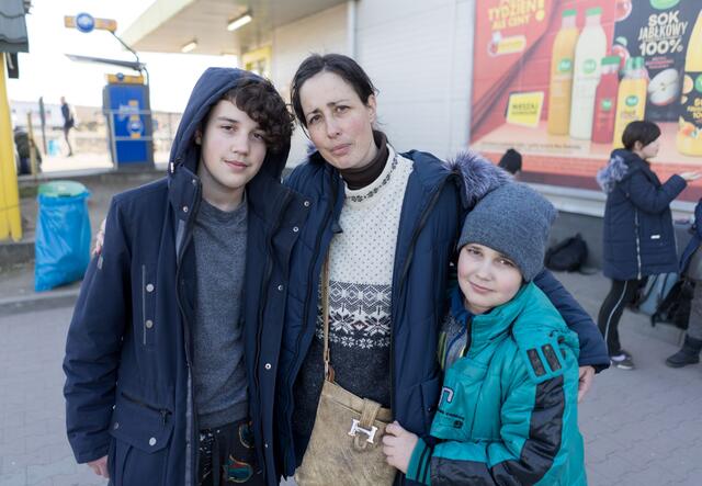 A woman, Oksana, standing with her arms around two children