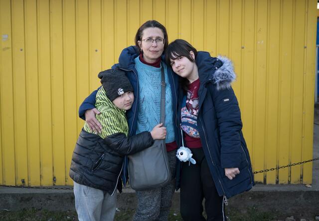 A woman, Marta, standing with her arms around her two children