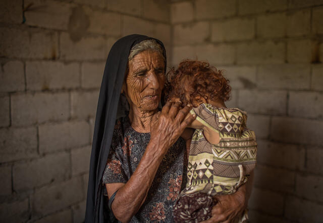 Fatma Salim Qebas holds her toddler granddaughter inside their home 