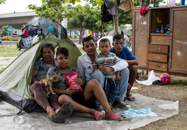 52-year-old chef and grandmother Meli Rondon sits inside a tent with members of her family and their dog, Beethoven