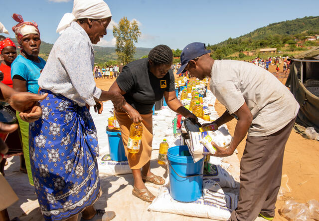 tow IRC aid workers help a woman pack a bottle of cooking oil and other food aid and emergency supplies in Machongwe, Zimbabwe