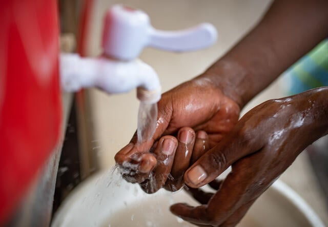A health worker in the Democratic Republic of Congo washes his hands at a water tap