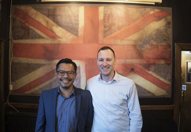 Warren (left) and Darren stand in front of a Union Jack flag in London