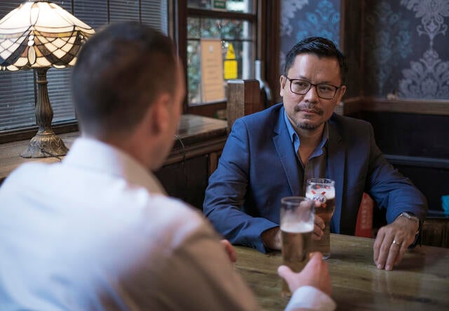 Darren and Warren talk at a pub table over over pints of beer