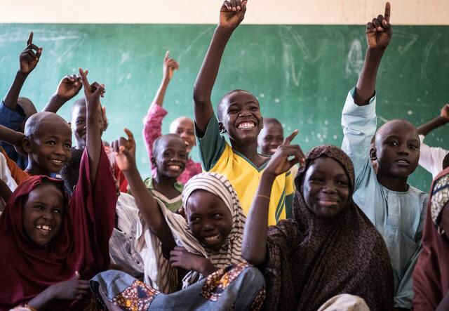 Students excitedly raise their hands in class at an International Rescue Committee supported school in Nigeria.