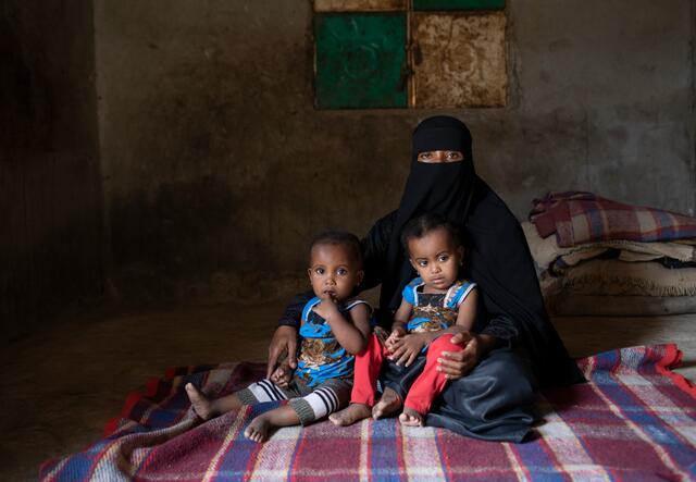 Fulla sits with her young twin daughters, who received medical help from the International Rescue Committee when they were diagnosed as acutely malnourished.