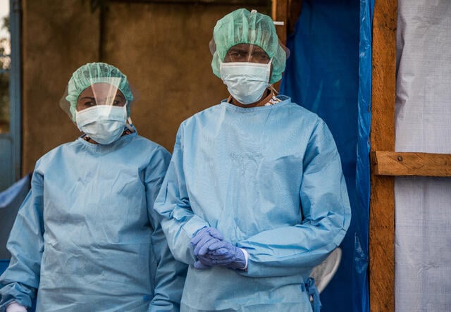 에볼라 환자 검진을 담당하는 국제구조위원회 지원 병원의 두 명의 의료진이 보호 장비를 착용하고 있습니다.