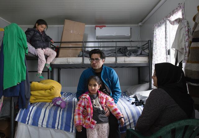 Parents and their two young children in their corrugated iron shelter in Moria refugee camp, Greece