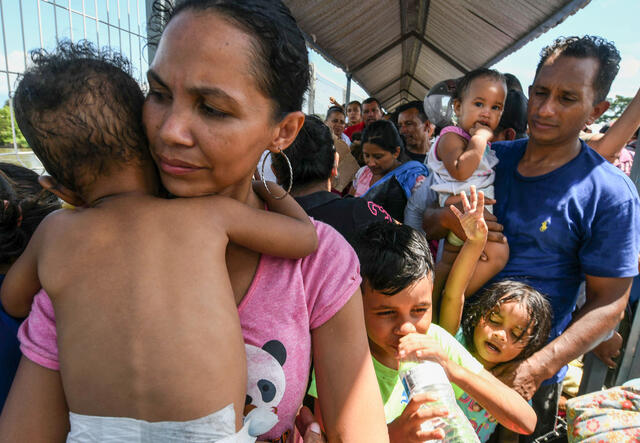 A Honduran migrant couple and their five kids taking part in a caravan heading to the U.S., wait to cross the border from Guatemala to Mexico