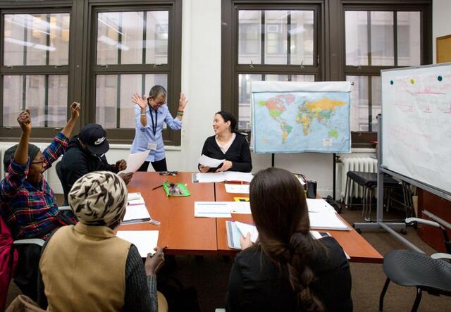 Adult education class siting in a rectangle seminar table, discussing class material